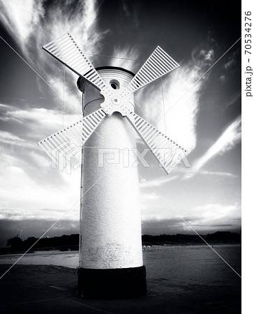 White windmill by sea on rocky coast. Seascape and landscape 70534276