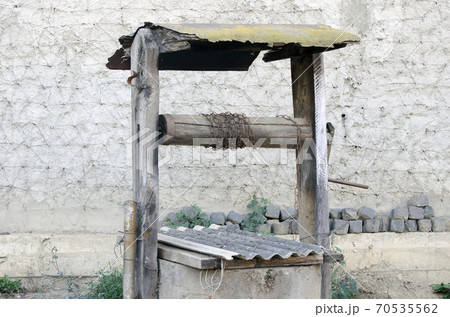 Old well on the background of the wall. Old well on the background of the wall. 70535562