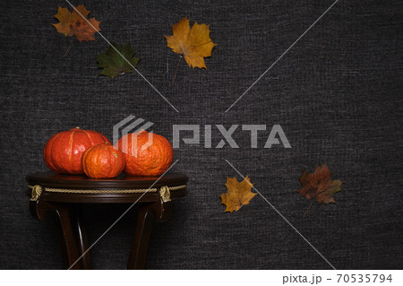 Colored pumpkins on wooden stool in front of a black backdrop. Colored pumpkins on wooden stool in front of a black backdrop. 70535794