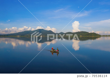 Fisherman on a boat for fishing and catching freshwater fish in nature lake or river with reflection in morning time in Asia in Thailand. People. 70536114