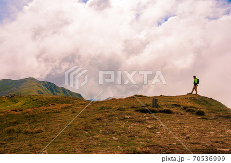 A tourist on top of the mountain opened his arms like a bird, enjoying the height and majesty of the mountains. A tourist on top of the mountain opened his arms like a bird, enjoying the height and majesty of the mountains. 70536999