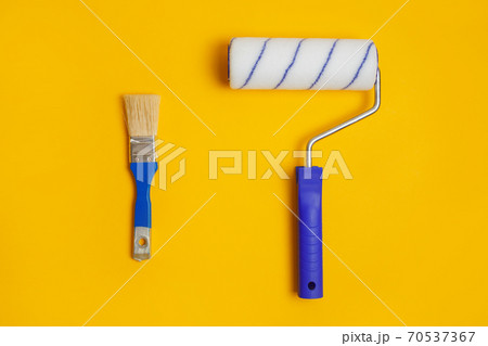 Paint roller and brush isolated on yellow. Painter tools for working with paint. 70537367