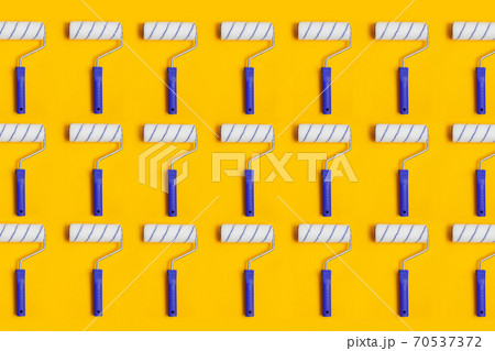 Pattern with paint roller with blue handle on yellow background. Clean roll for painting walls. 70537372