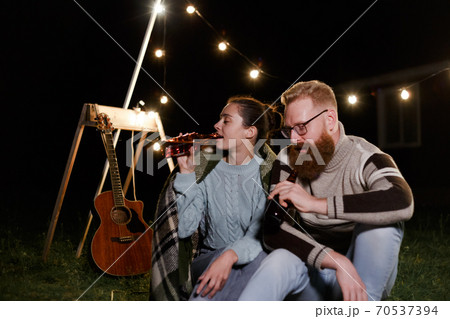 Friends having fun on the night picnic with drinks. Young caucasian couple at bbq in countryside 70537394
