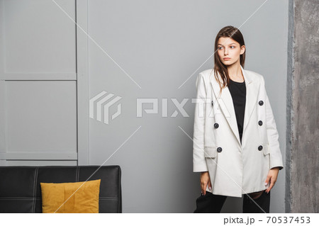 Young elegant woman in white oversize blazer and black ripped pants. Interior portrait Young elegant woman in white oversize blazer and black ripped pants. Interior portrait 70537453