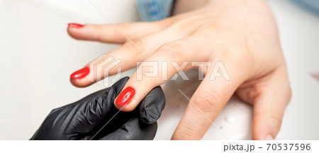 Young woman receives red nail polish Young woman receives red nail polish 70537596