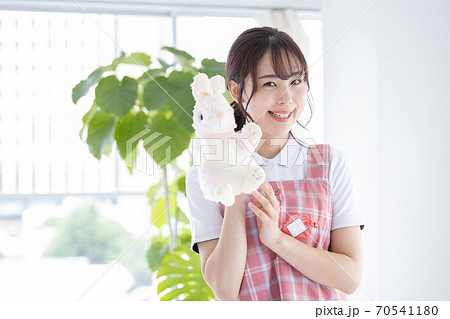 保育士ポートレート ぬいぐるみを持ちカメラ目線で微笑む保育士の写真素材