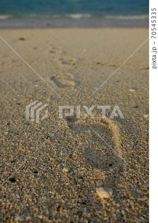海に向かって歩いている砂浜についた足跡の写真素材
