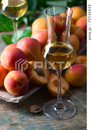Juicy apricots with leaves and glass of sweet wine . 70546839
