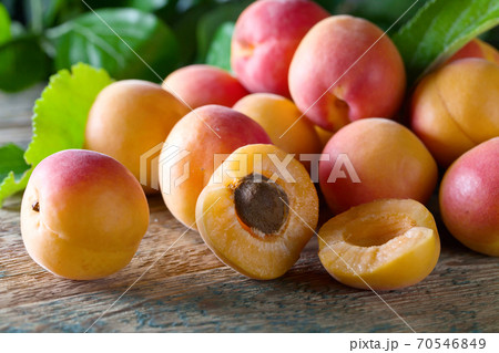Juicy fresh apricots with leaves on old wooden table . 70546849