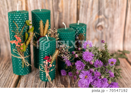 Handmade honey candles made from natural wax on a background of wooden boards. Elements made from natural materials. Christmas or New Year composition. Photo for a postcard. 70547192