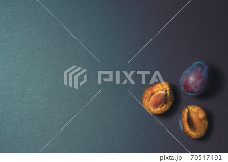 three ripe plums on a kitchen stone table close up 70547491