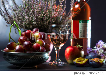 ripe grapes with a glass of wine with an apple with plums and flowers 70547493