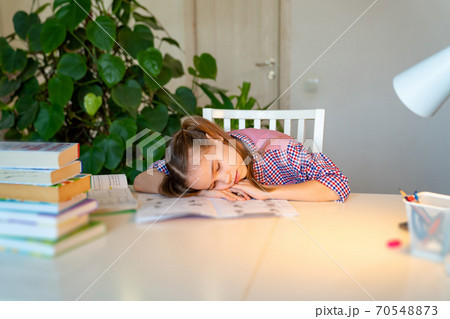 schoolgirl asleep doing homework. studying at home schoolgirl asleep doing homework. studying at home 70548873