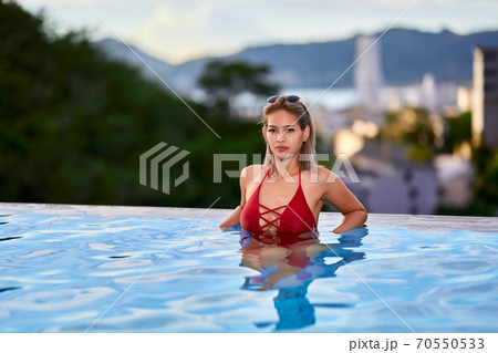 Young asian woman in red swimsuit posing at swimming pool 70550533