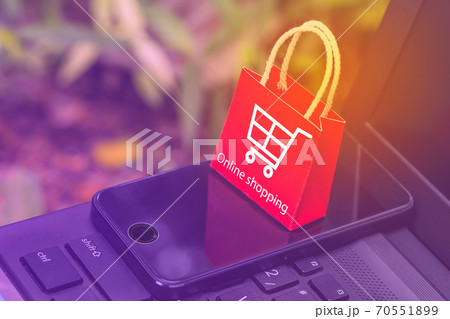 Mini red paper shopping bags with mobile phone on a laptop keyboard. Concept about online shopping that customers can buy everything from home or office. Via the tool electronics. Mini red paper shopping bags with mobile phone on a laptop keyboard. Concept about online shopping that customers can buy everything from home or office. Via the tool electronics. 70551899