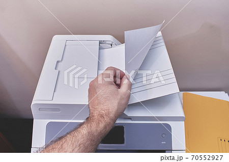 Caucasian or white man making photocopies on a copier or printer in an office Caucasian or white man making photocopies on a copier or printer in an office 70552927