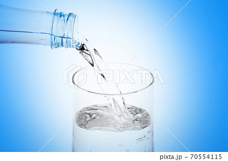 Pouring water from plastic bottle into glass on white background. 70554115