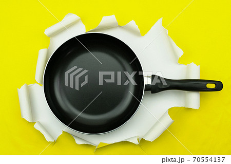 Top view of Kitchen utensil pan on yellow torn paper background. 70554137