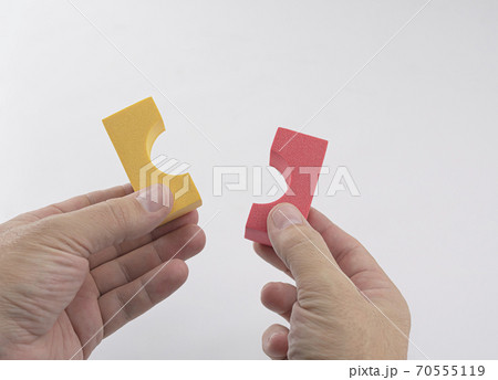 hands of caucasian man with two pieces of colored foam construction for children on white background hands of caucasian man with two pieces of colored foam construction for children on white background 70555119