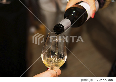 Person serving a glass of wine in glass cup in a dark cellar Person serving a glass of wine in glass cup in a dark cellar 70555300