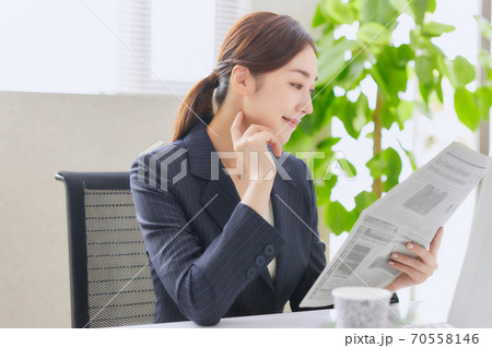 オフィスで英字新聞を読むキャリアウーマン 70558146