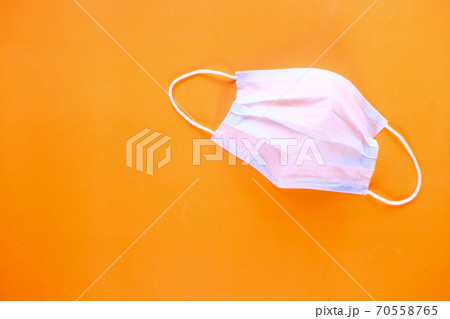 Close up of blue surgical masks on orange background Close up of blue surgical masks on orange background 70558765