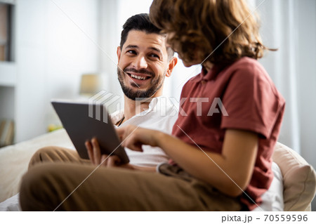 Father and son are sitting with a tablet 70559596