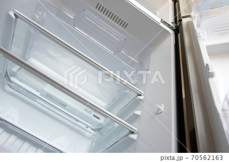 Open new fridge. Empty refrigerator with open door, view from below. 70562163