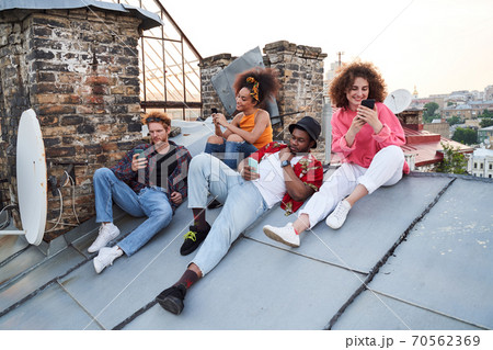 Jolly young people surfing internet together outdoors Jolly young people surfing internet together outdoors 70562369