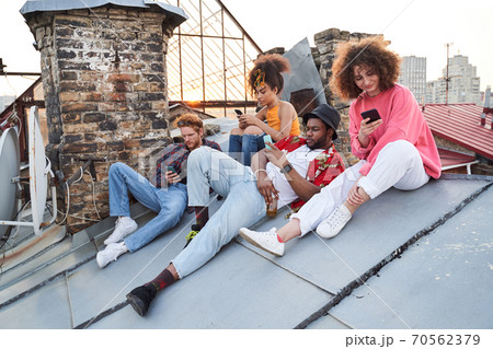 Cheerful young people using smartphones on roof Cheerful young people using smartphones on roof 70562379