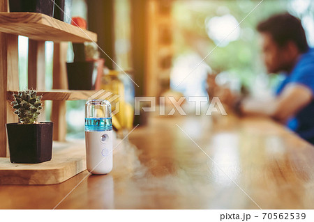 Alcohol nano mist sprayer for hand cleaning to prevent the spread of the Corona virus (Covid-19) to serve customers at coffee shop. Modern health technology. New normal lifestyle. Selective focus Alcohol nano mist sprayer for hand cleaning to prevent the spread of the Corona virus (Covid-19) to serve customers at coffee shop. Modern health technology. New normal lifestyle. Selective focus 70562539