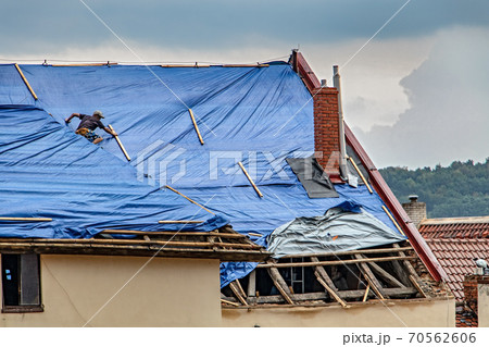 The roofer works on roof when is rain.  70562606