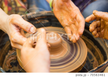 A close up view on ceramic production process on potter's wheel with children. Clay crafts with kids concept A close up view on ceramic production process on potter's wheel with children. Clay crafts with kids concept 70563461