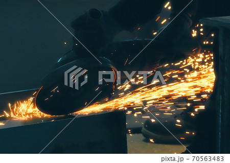 Professional worker cuts metal by angle grinder machine. Fountain of sparks. Fire safety at construction site. Professional worker cuts metal by angle grinder machine. Fountain of sparks. Fire safety at construction site. 70563483