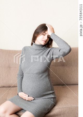 Young pregnant woman suffering from headache on sofa in home. Maternity healthcare concept 70564311