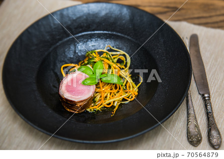 Tenderloin wrapped in bacon with zucchini carrot noodles 70564879