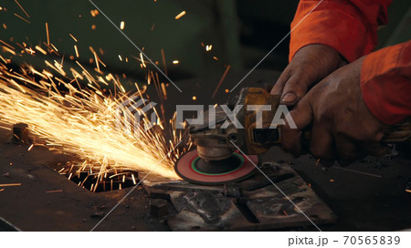 Professional mechanic is cutting steel metal. 70565839