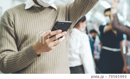 Traveler wearing face mask while using mobile phone on public train Traveler wearing face mask while using mobile phone on public train 70565993