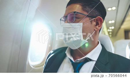 Traveler wearing face mask while traveling on commercial airplane . 70566044
