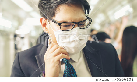 Young man wearing face mask travels on crowded subway train Young man wearing face mask travels on crowded subway train 70566102