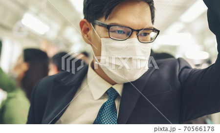 Young man wearing face mask travels on crowded subway train 70566178