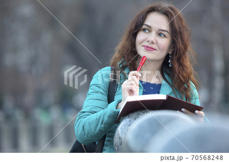 Portrait of a beautiful smiling girl with a red pen in her hand Portrait of a beautiful smiling girl with a red pen in her hand 70568248