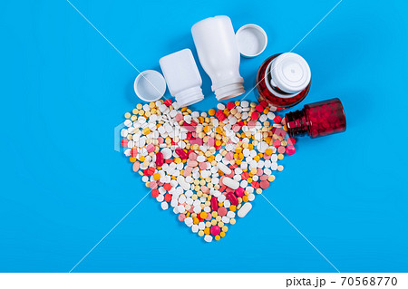 Medical pills and tablets spilling out of a drug bottle on blue background 70568770