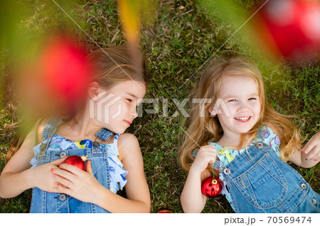 girls lie on grass under palm with Christmas toys. girls lie on grass under palm with Christmas toys. 70569474