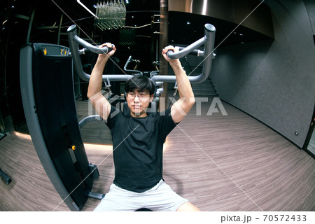 ASian male doing exercise for chest muscles on pec deck machine during workout in gym.The sport and healthy lifestyle concept. 70572433