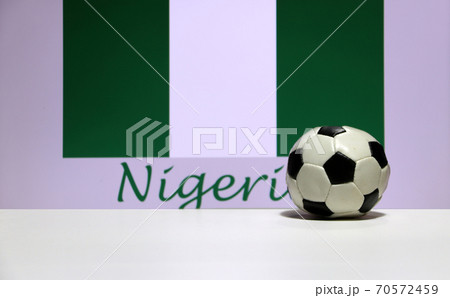 Small football on the white floor and Nigerian nation flag with the text of Nigeria background.  70572459