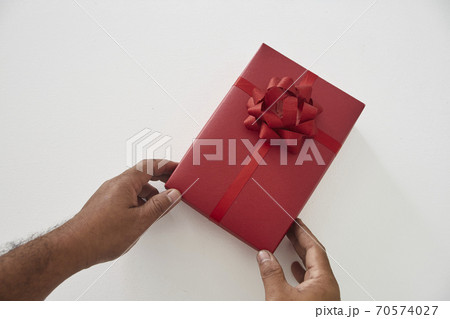 Man hands holding a red gift box on a white 70574027