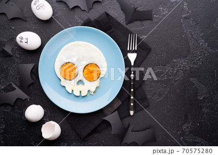 Fried eggs in the shape of a skull. Halloween breakfast. 70575280