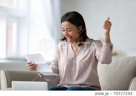 Excited biracial woman triumph reading good news in letter Excited biracial woman triumph reading good news in letter 70577292